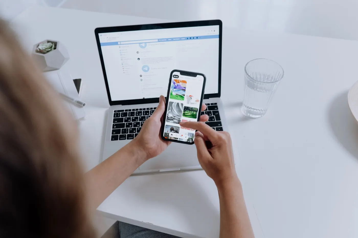 Someone working across a phone and a laptop at once