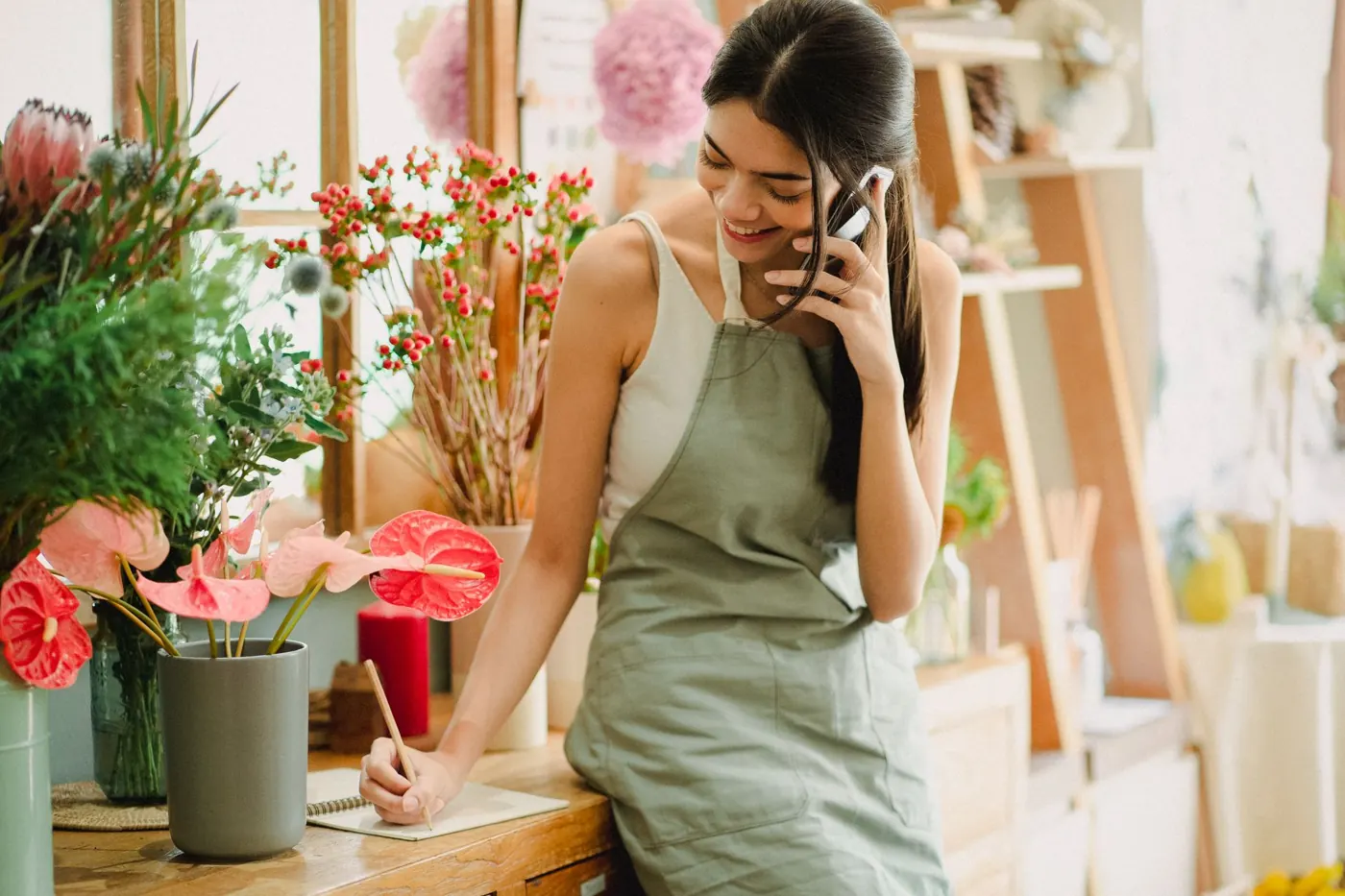 A florist smiling as she talks on her phone in her shop