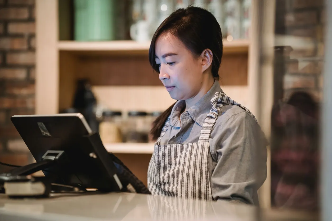 A café owner at the counter, working on the till
