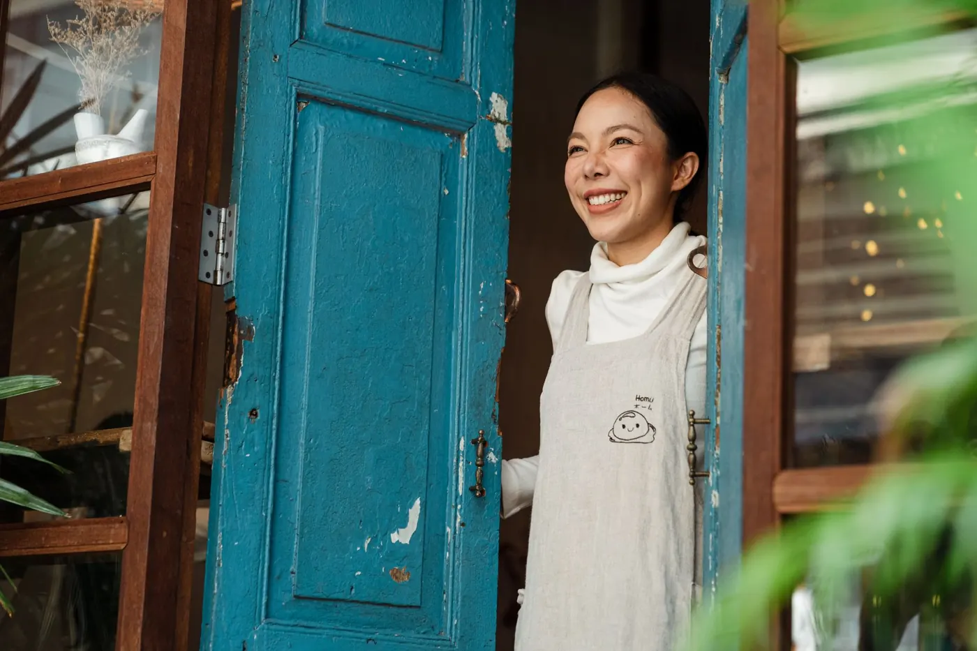 A shop owner smiling at the door of her shop